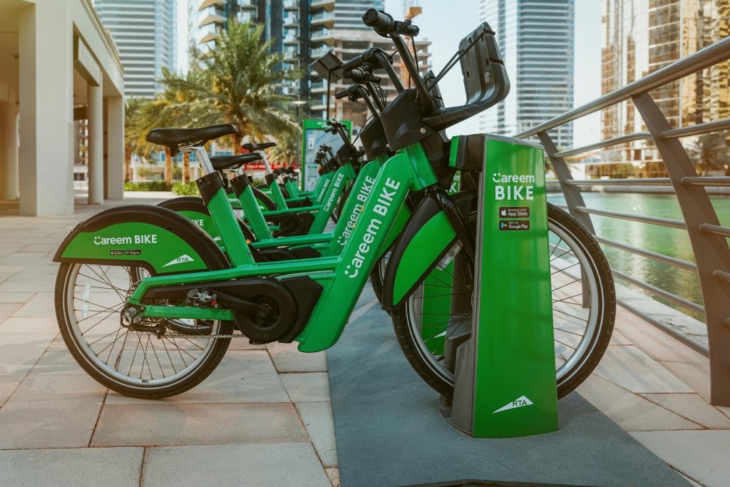 Green Careem bikes parked in a row at a docking station by Dubai Marina. Urban transportation solution.