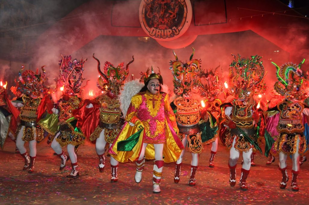Dancers in ornate, colorful costumes with elaborate masks performing La Diablada during the Carnaval de Oruro in Bolivia, a UNESCO-recognized festival blending Andean and Catholic traditions.