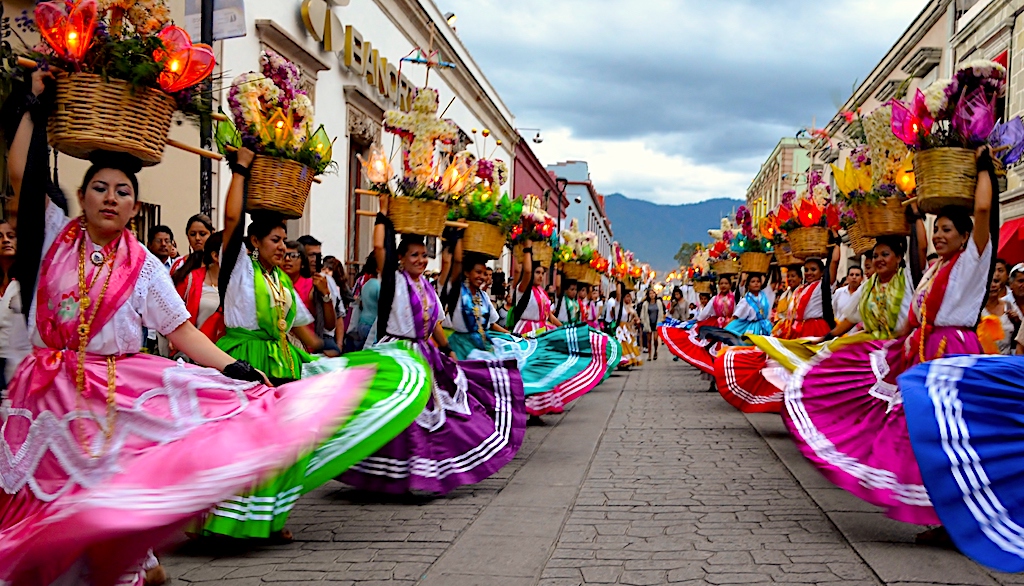 Performers in colorful traditional costumes dancing during the Guelaguetza festival in Oaxaca, Mexico, a vibrant celebration of indigenous cultures and regional traditions.