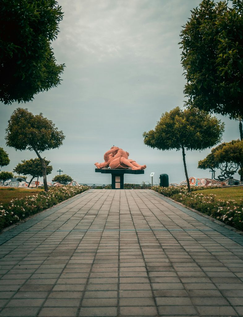Romantic El Beso sculpture at Love Park in Miraflores, Lima, amid lush gardens.