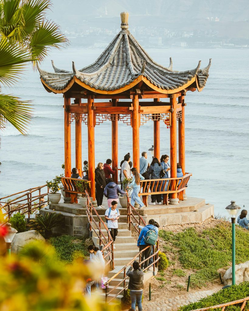Visitors gather at a Chinese pavilion by the seaside in Miraflores, Lima, Peru, enjoying ocean views.